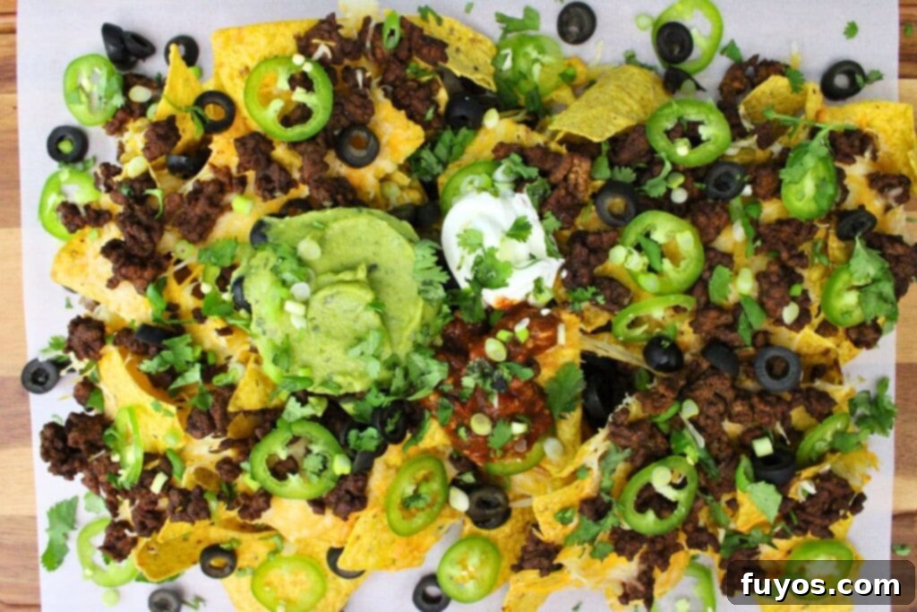 The Ultimate Air Fryer Nachos for Game Day 12 overhead view of air fryer nachos with ground beef, guacamole, and sour cream