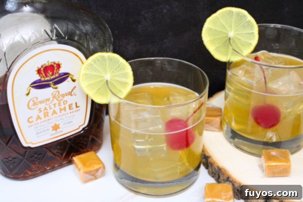 Two glasses of salted caramel whiskey sour with cherry and lemon garnishes against a dark background