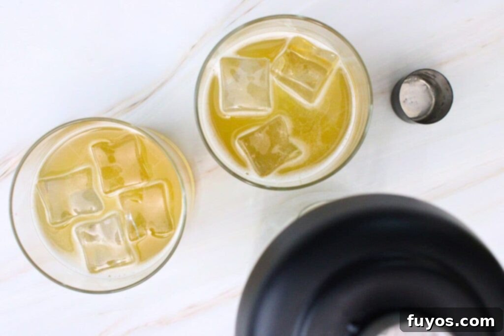 Straining a freshly shaken salted caramel whiskey sour over ice into a glass