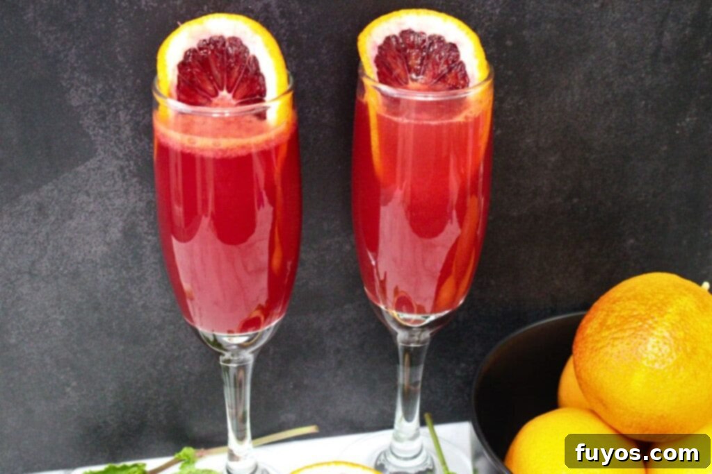 Your Simple 3 Ingredient Blood Orange Mimosa for Winter Brunch 8 closeup view of two blood orange mimosas in champagne flutes with blood orange slices in the rim