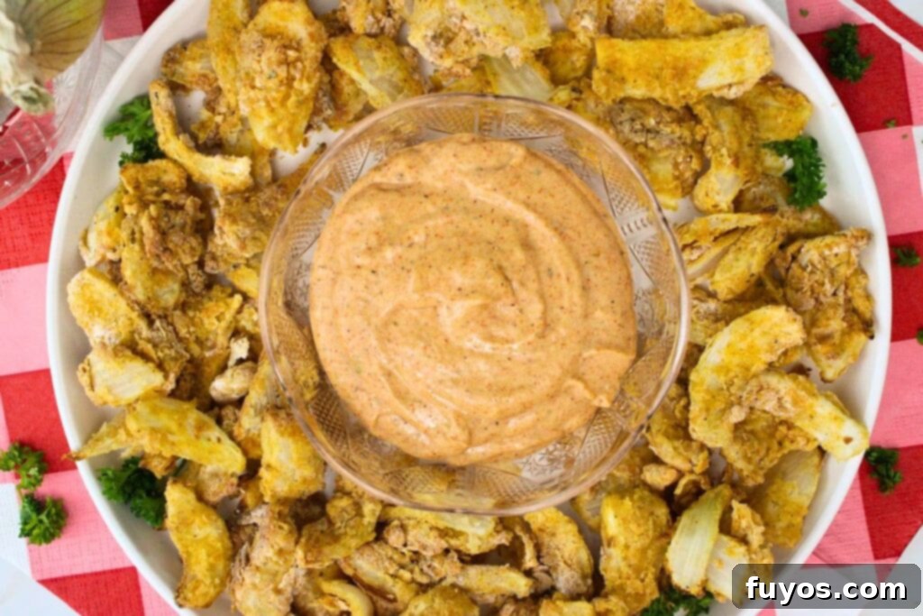 overhead view of air fryer blooming onion petals on a plate with blooming onion dipping sauce