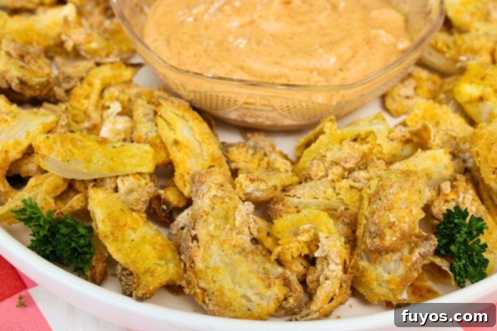 closeup of air fryer blooming onion on a plate with dipping sauce