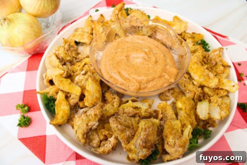 easy air fryer blooming onion petals surrounding a bowl of dip on a plate
