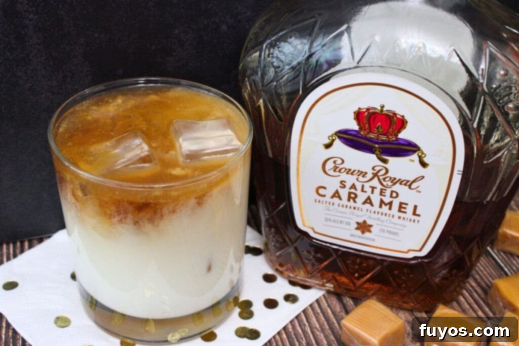 Salted Caramel Royal White Russian Bliss 8 A perfectly chilled Crown Royal Salted Caramel White Russian cocktail in a whiskey glass, with ice cubes, next to a bottle of Crown Royal Salted Caramel whiskey, symbolizing the drink's main ingredient.