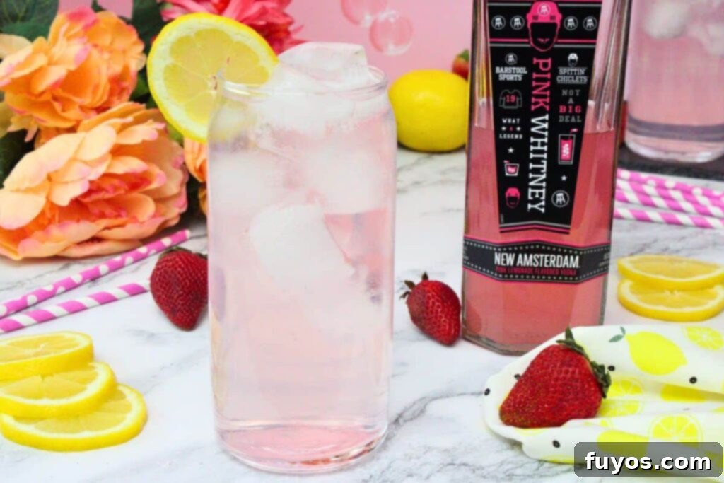 Pink Whitney and Sprite Recipe Easy 2 Ingredient Cocktail 3 A tall glass of Pink Whitney and Sprite, garnished with a fresh lemon slice, sits beside a bottle of Pink Whitney vodka, highlighting the ingredients.