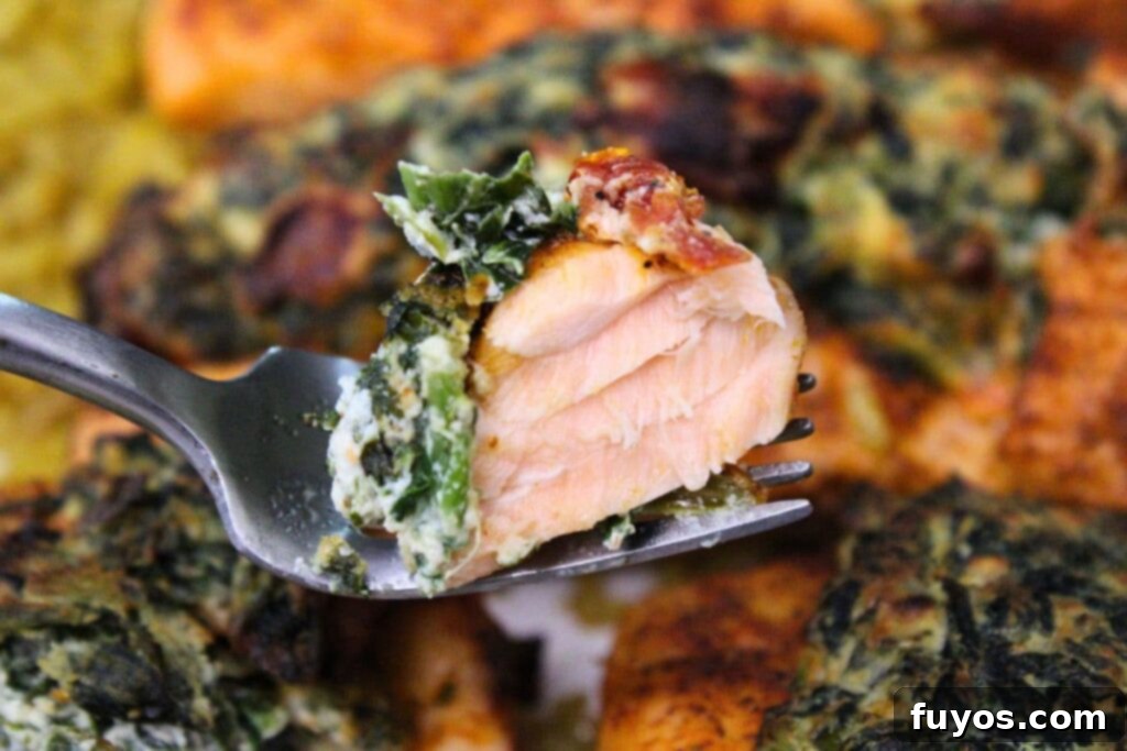 Holding up a fork with a piece of flaky air fryer spinach stuffed salmon, showing the delicious filling