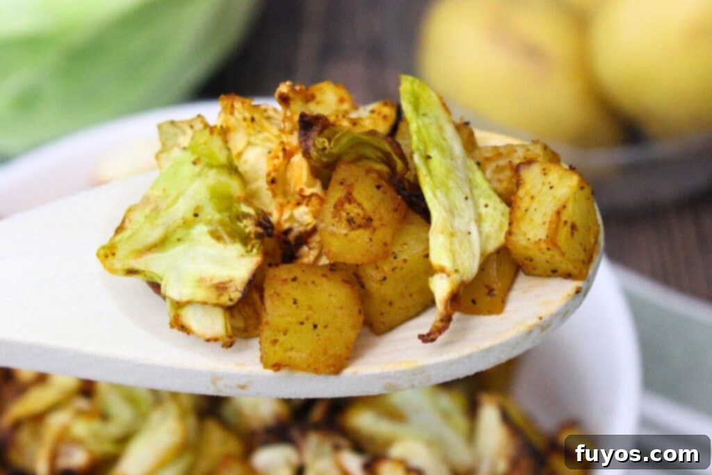 Simple Air Fryer Cabbage and Potatoes 3 holding up a wooden spoon with air fryer cabbage and potatoes