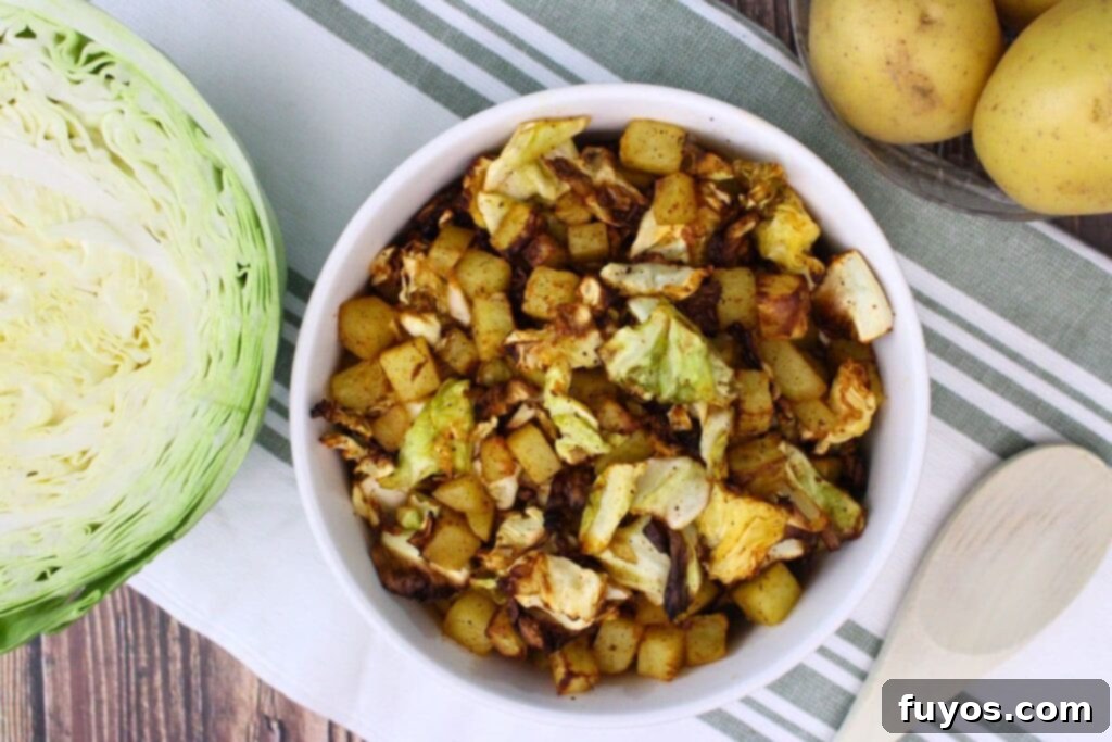 Simple Air Fryer Cabbage and Potatoes 8 overhead view of air fryer cabbage and potatoes in a bowl next to half a head of cabbage