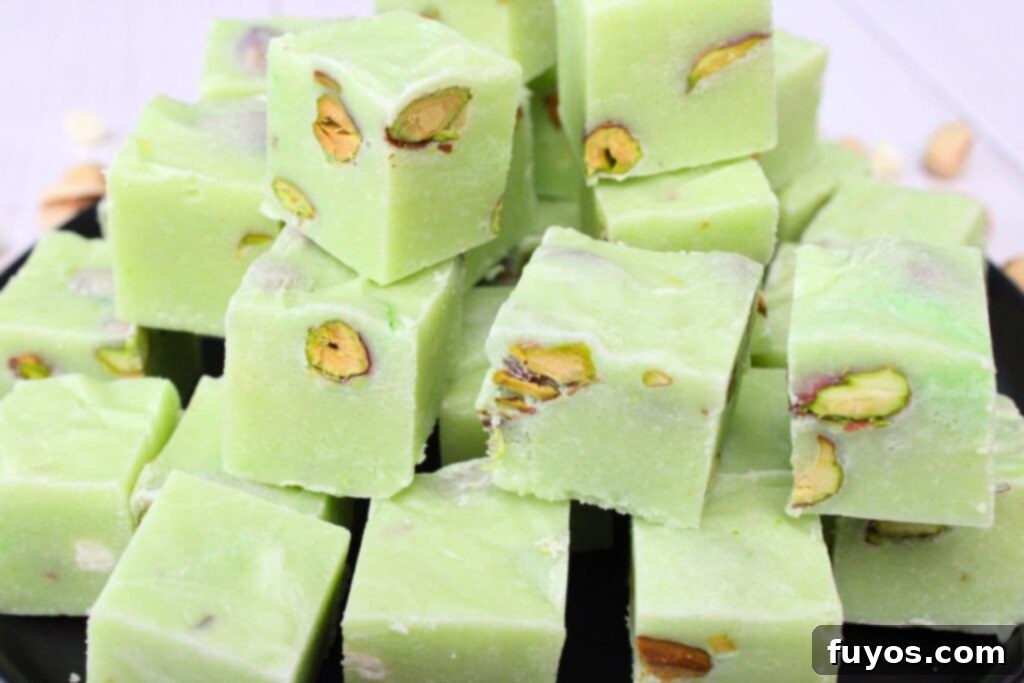 4 Ingredient Microwave Pistachio Fudge Delight 9 close up view of decadent pistachio fudge cubes stacked up on a plate, highlighting their rich texture and nut inclusions
