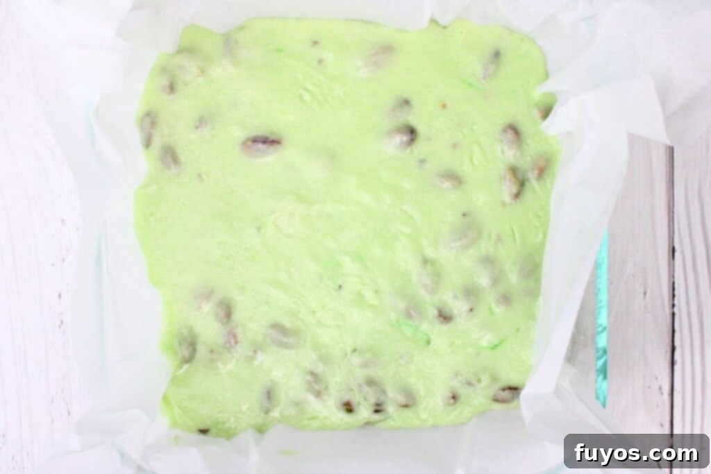 4 Ingredient Microwave Pistachio Fudge Delight 7 pouring the vibrant green pistachio fudge mixture into the parchment-lined pan