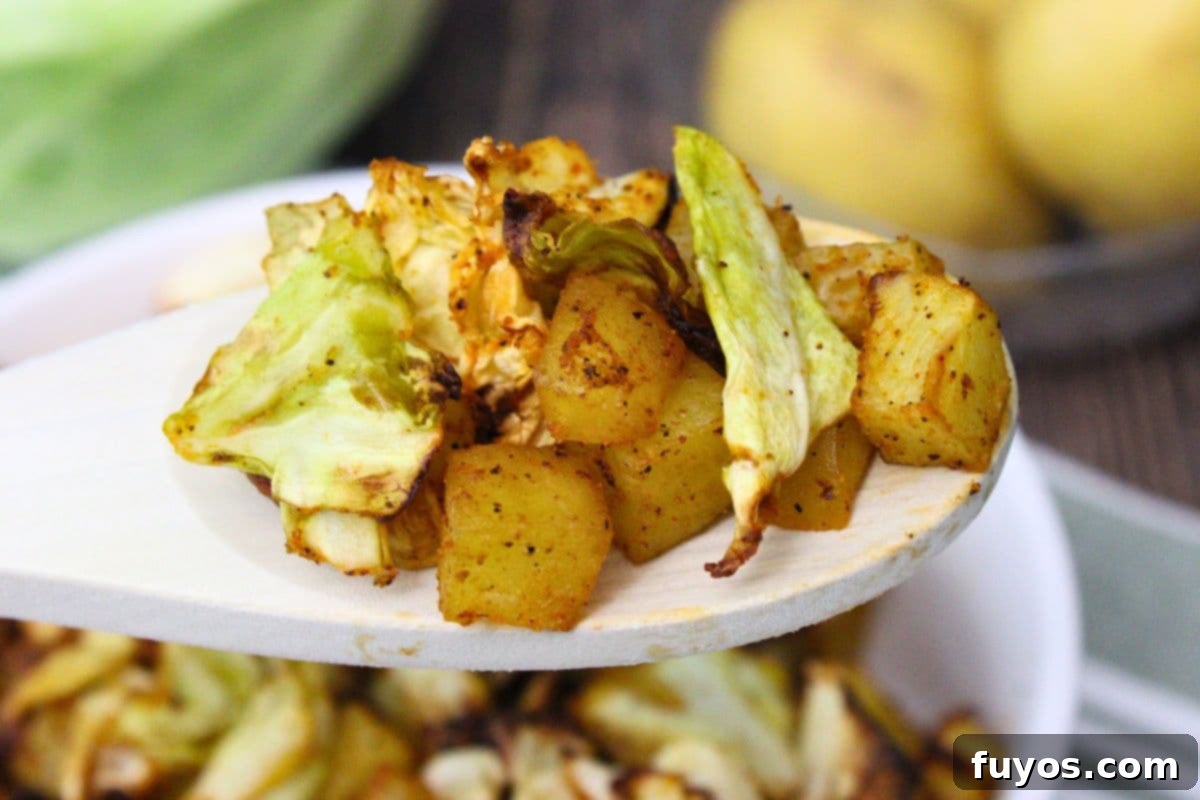 Holding up a wooden spoon with air fryer cabbage and potatoes, a comforting side