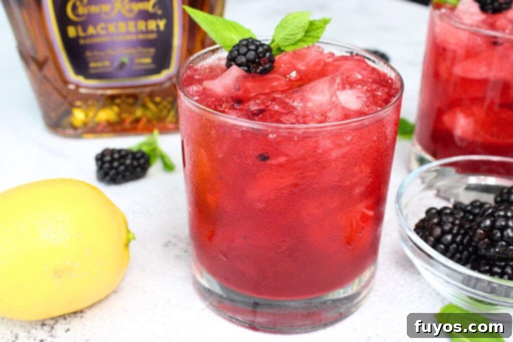 closeup view of blackberry smash cocktail with fresh fruit and crown royal bottle