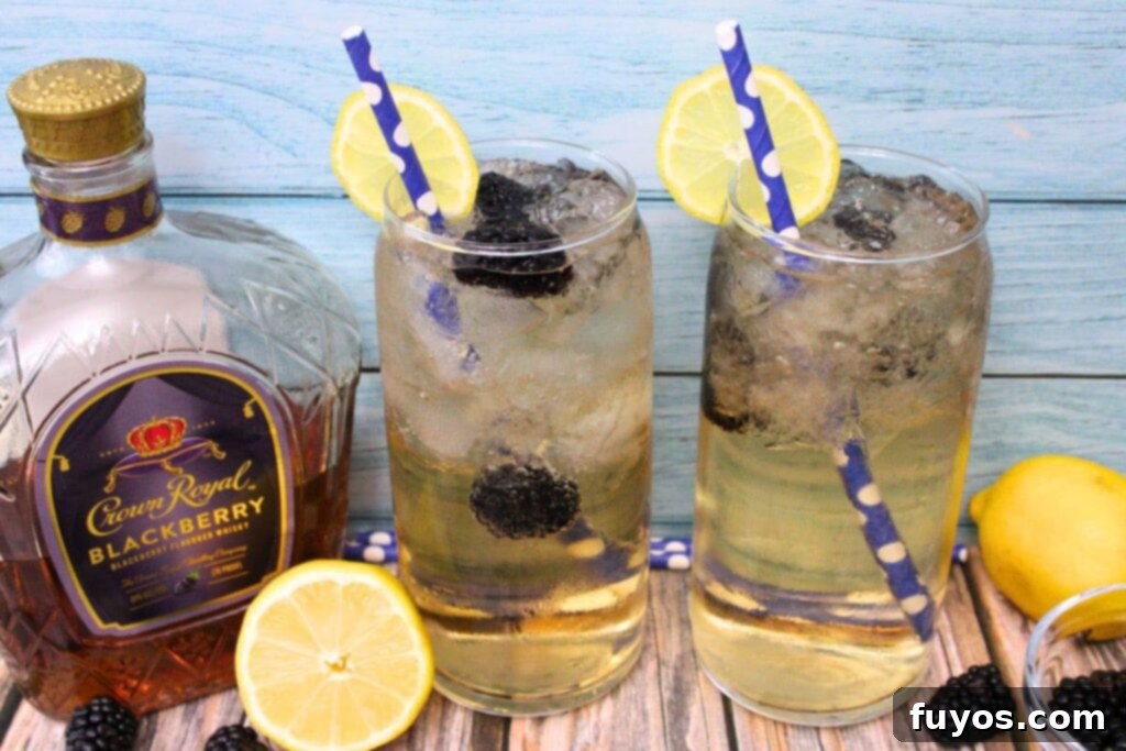 Two tall glasses of Crown Royal Blackberry and Sprite cocktail sit on a blue wooden background, with the Crown Royal Blackberry bottle in the frame.