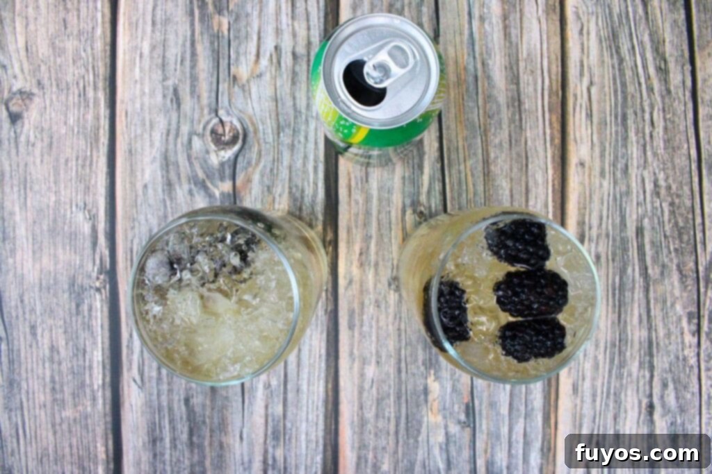 Pouring Sprite soda over Crown Royal Blackberry whiskey and ice in tall glasses.