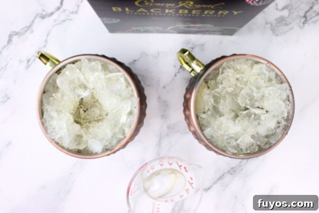 Adding Crown Royal Blackberry whiskey and fresh lime juice to a copper mug with ice.