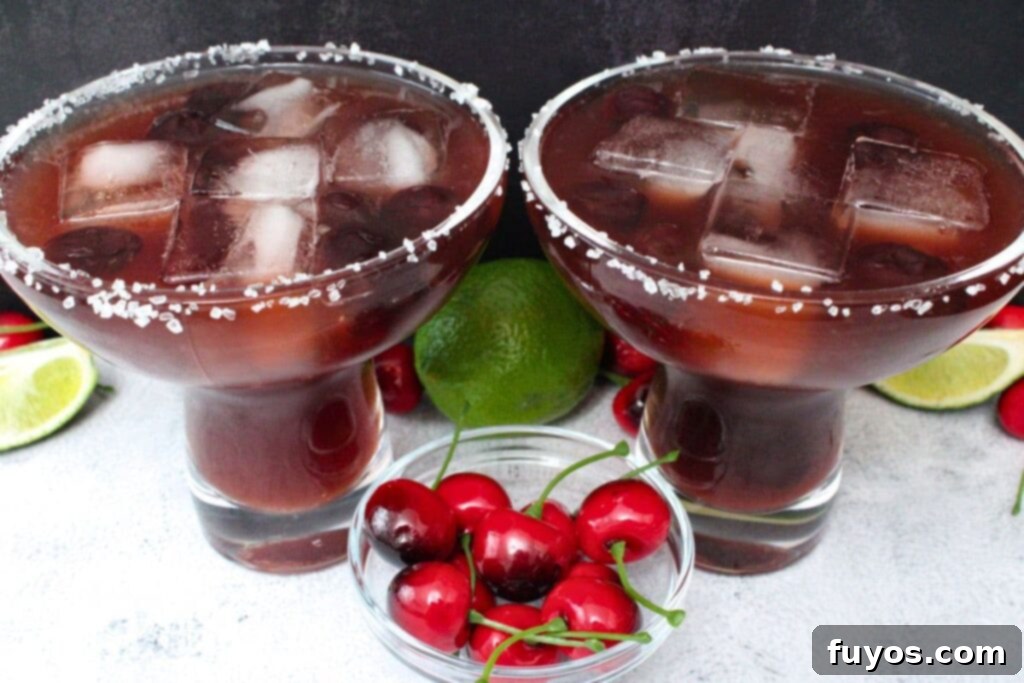 Black Cherry Tequila Burst 3 two black cherry margarita cocktails against a dark background with limes