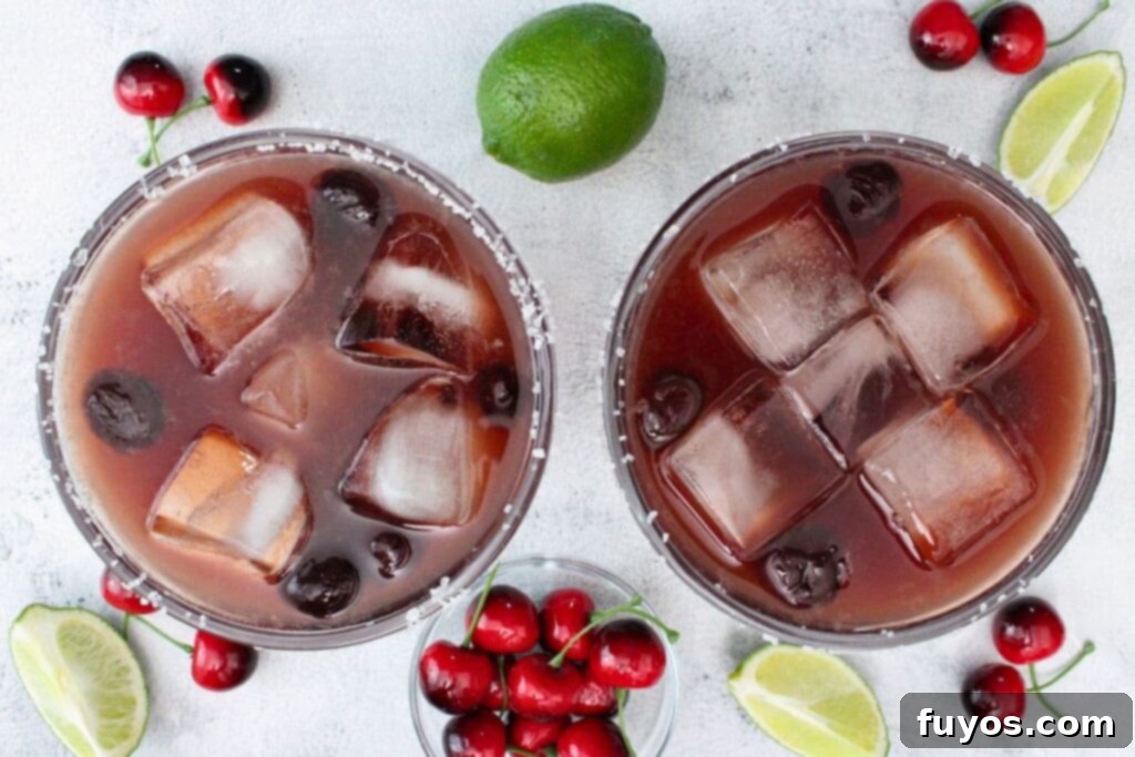 Black Cherry Tequila Burst 8 overhead view of two black cherry margarita drinks surrounded by lime and cherries