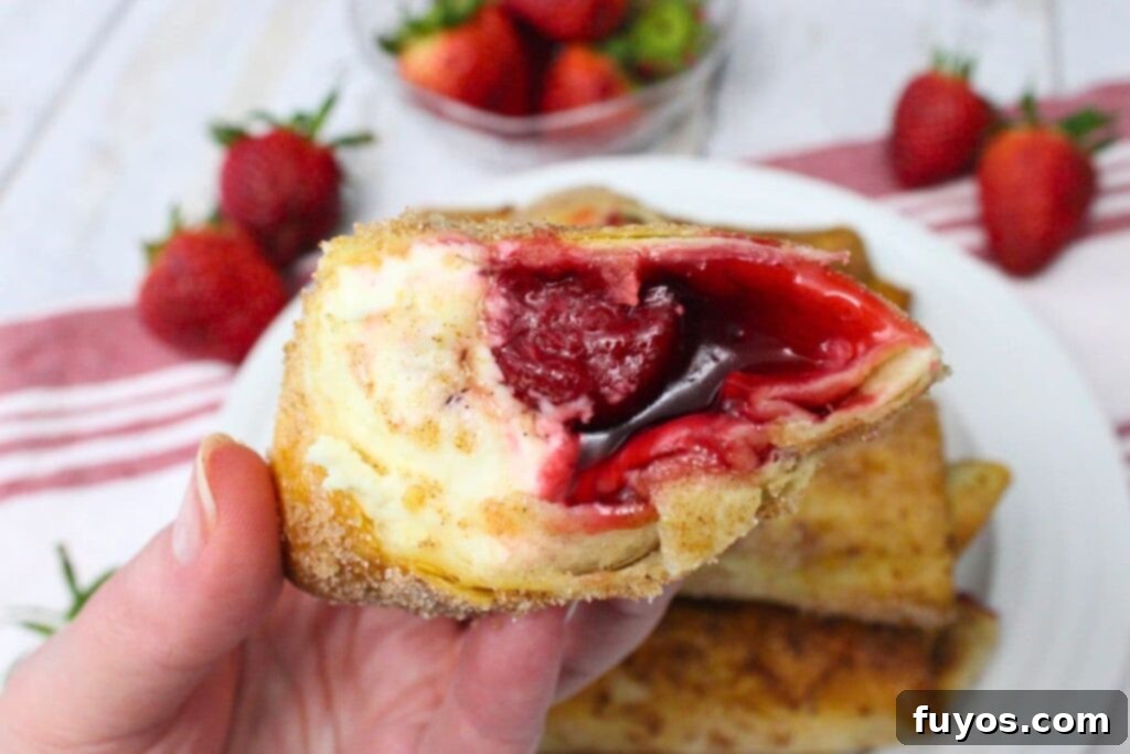 holding up half of an air fryer cheesecake chimichanga to show the gooey insides
