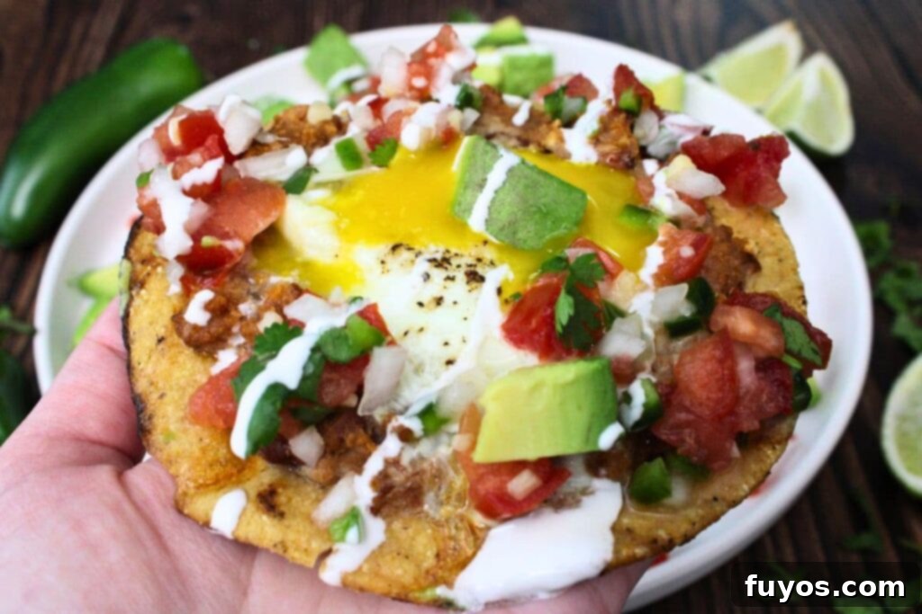 Air Fried Huevos Rancheros Zesty Mexican Breakfast 3 holding up an air fryer huevos rancheros topped with pico de gallo, avocado, and crema
