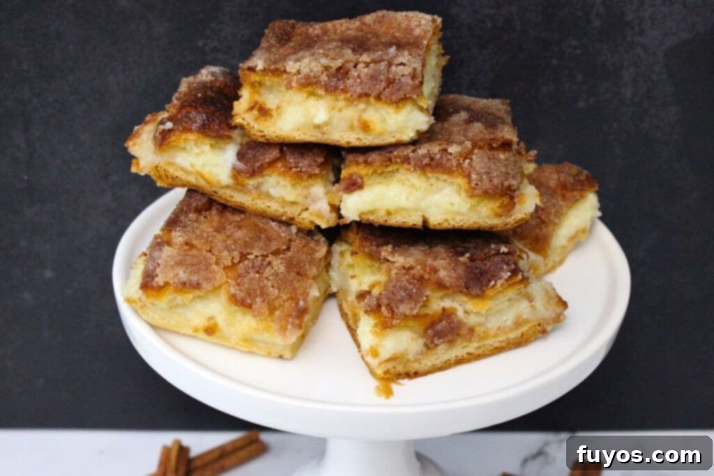 air fryer sopapilla cheesecake bars stacked up on a white pedestal plate