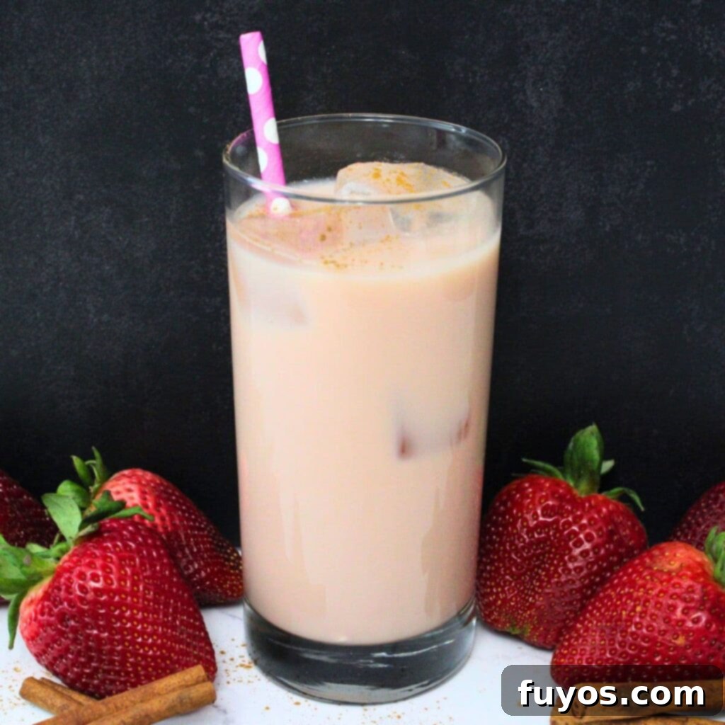 Dutch Bros Inspired Strawberry Horchata Chai 2 A vibrant glass of Dutch Bros copycat Strawberry Horchata Chai, garnished with fresh strawberries and a cinnamon stick, ready to be enjoyed.