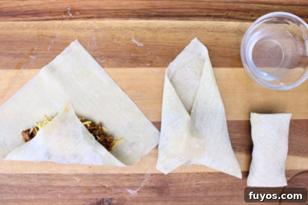 carefully roll up the egg roll wrapper over the beef and cheese filling