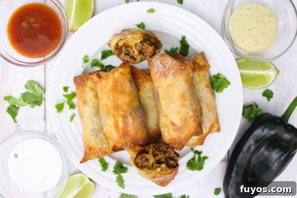 overhead view of air fryer taco egg rolls stacked on a plate with dipping sauces on the side