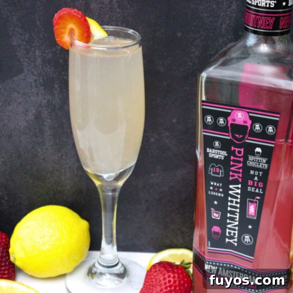Pink Whitney Infused Strawberry Pink Lemonade Mimosa 2 Two sparkling pink lemonade mimosas, garnished with fresh strawberries, in elegant champagne flutes, set against a bright, airy background, perfect for a spring or summer brunch.