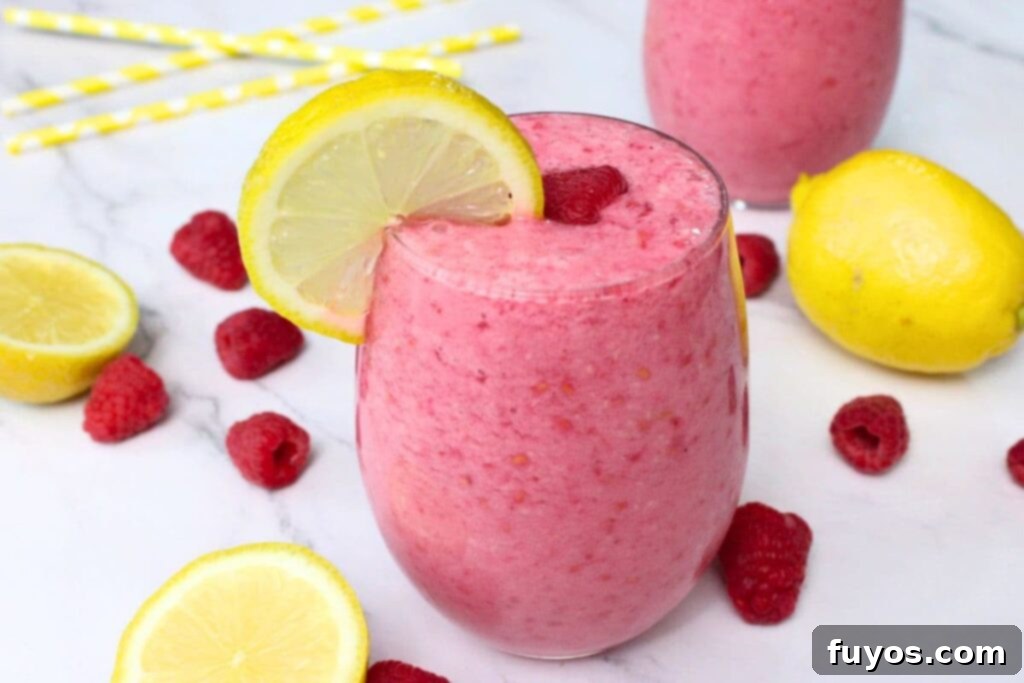 Beat the Heat with a Raspberry Lemonade Smoothie 8 raspberry lemonade smoothie drink on a white countertop surrounded by fruit and straws