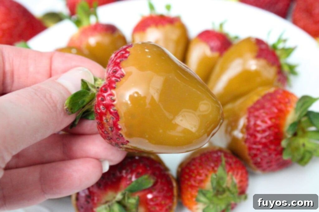 Two Ingredient Caramel Strawberry Delight 3 holding up a caramel coated strawberry