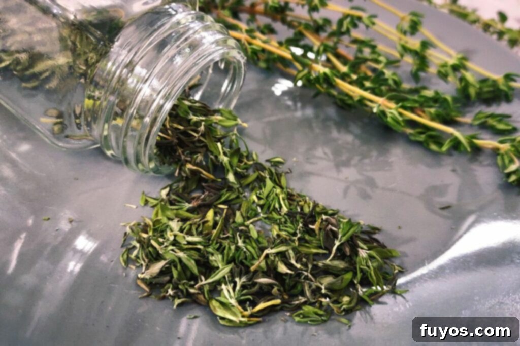 Effortless Microwave Thyme Drying 2 closeup of microwave dried thyme spilling out of a glass spice jar on a plate