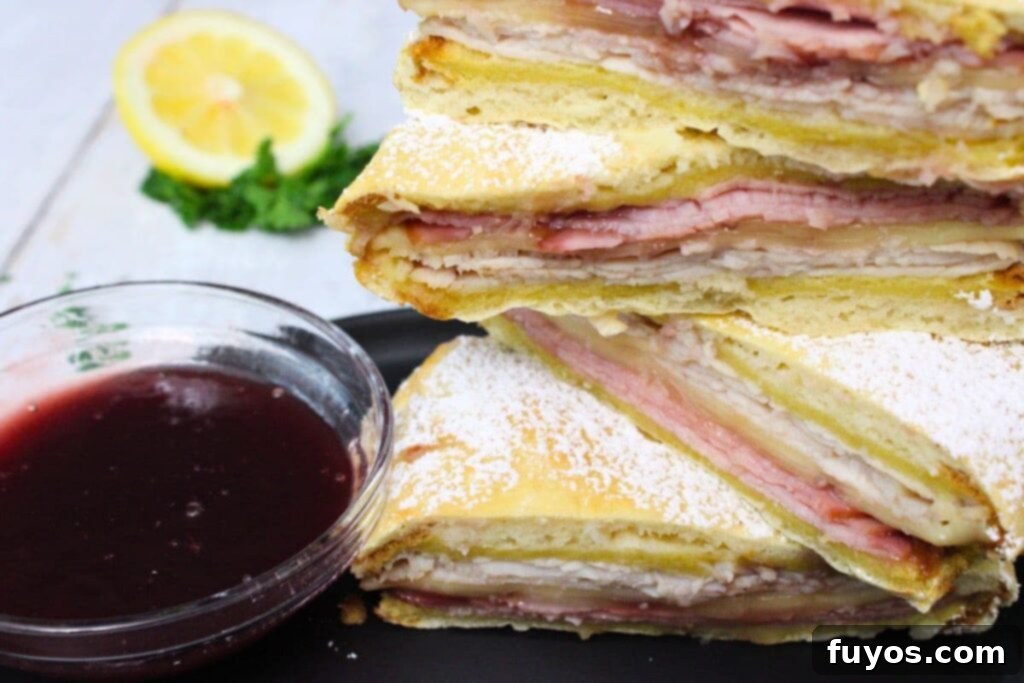 Air Fryer Monte Cristo A Taste of Disneyland 3 halves of air fryer monte cristo stacked on top of each other next to a bowl of raspberry jam