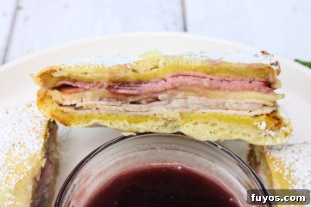 Air Fryer Monte Cristo A Taste of Disneyland 9 closeup view of half an air fryer monte cristo sandwich leaned against a small bowl of raspberry jam