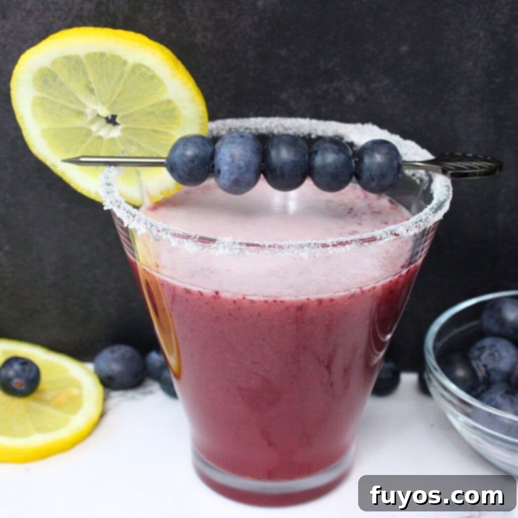 Two vibrant blueberry lemon drop martinis, garnished with fresh blueberries and lemon slices, ready to be enjoyed.