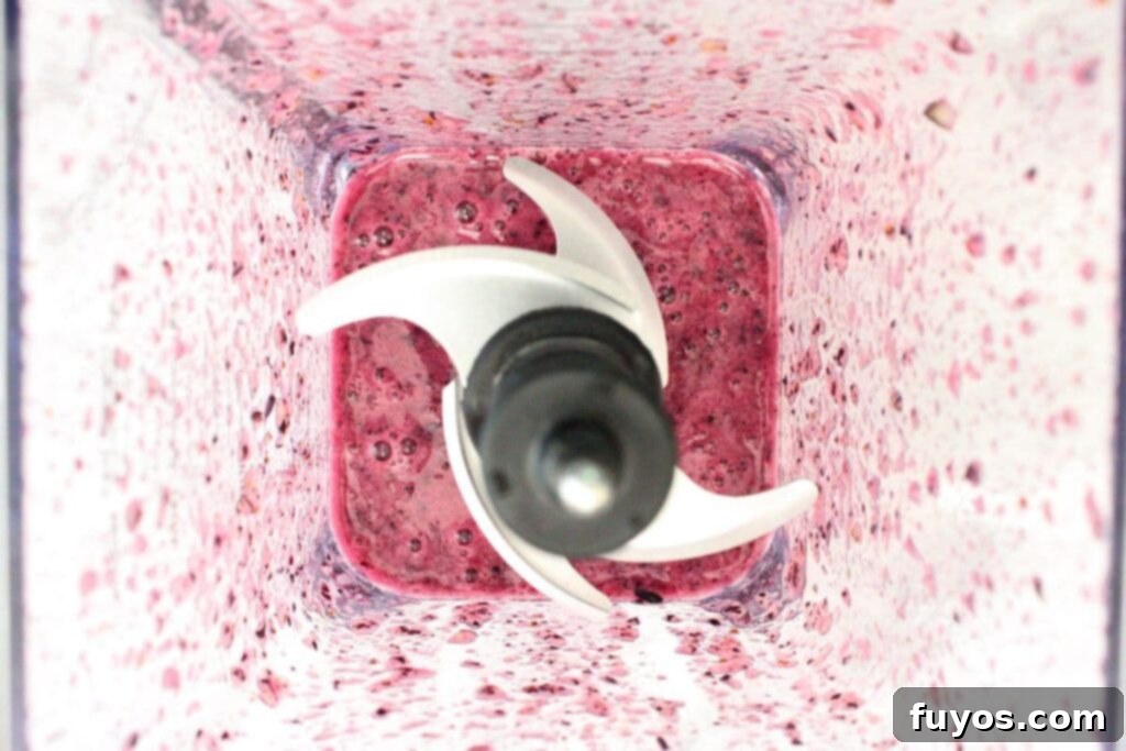 Blueberries being blended in a food processor until a smooth, vibrant puree forms.