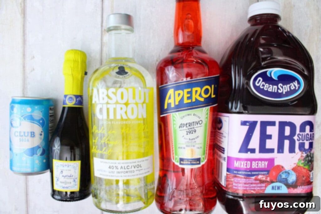 various ingredients laid out on a table to make a spring spritzer cocktail, including vodka, aperol, berry juice, prosecco, and club soda