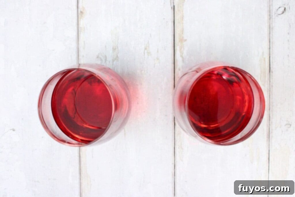 combining vodka, aperol, and fruit juice in a wine glass for the spring spritzer cocktail
