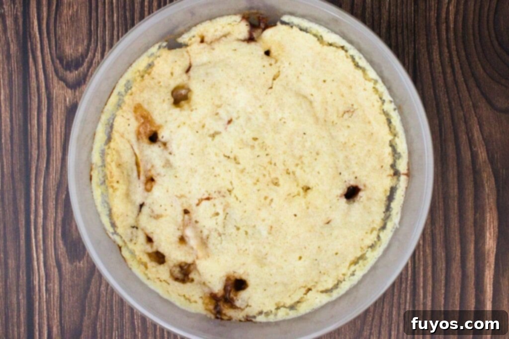 Step 4: The peach cobbler in the microwave-safe dish after cooking, showing bubbly peaches and a set topping.