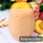 Peach Strawberry Mango Summer Bliss Smoothie 9 A close-up of a peach strawberry mango smoothie in a glass, with the title Peach Strawberry Mango Smoothie Recipe for Pinterest
