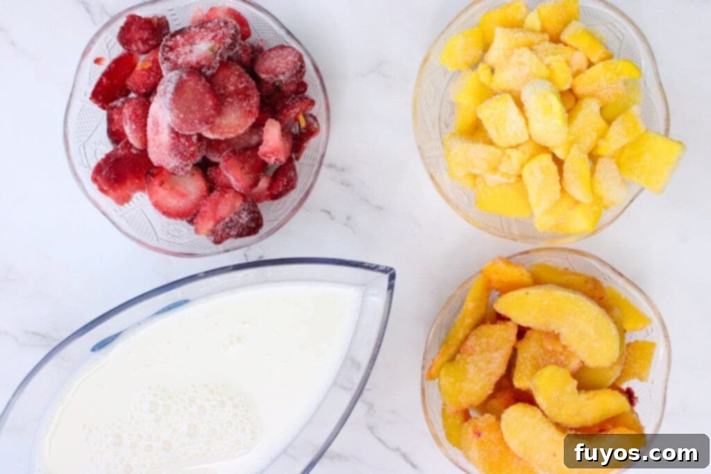 Peach Strawberry Mango Summer Bliss Smoothie 4 Fresh and frozen ingredients laid out for making the peach strawberry mango smoothie, including frozen strawberries, mango, peach slices, and almond milk.