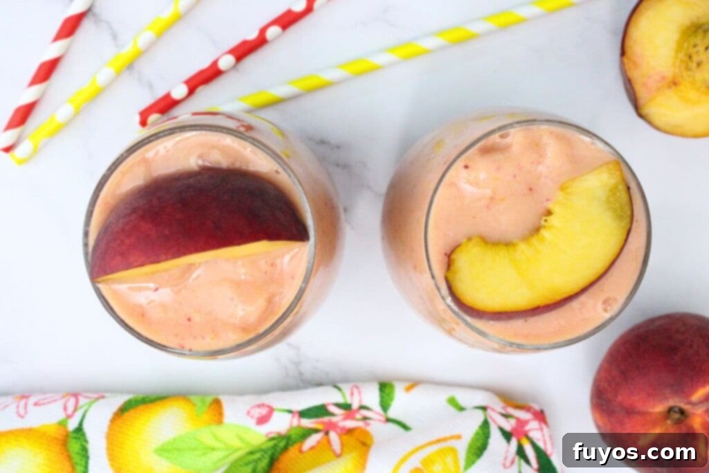 Peach Strawberry Mango Summer Bliss Smoothie 6 An overhead view of two delicious peach strawberry mango smoothies, garnished with fresh peach slices, ready to be served.