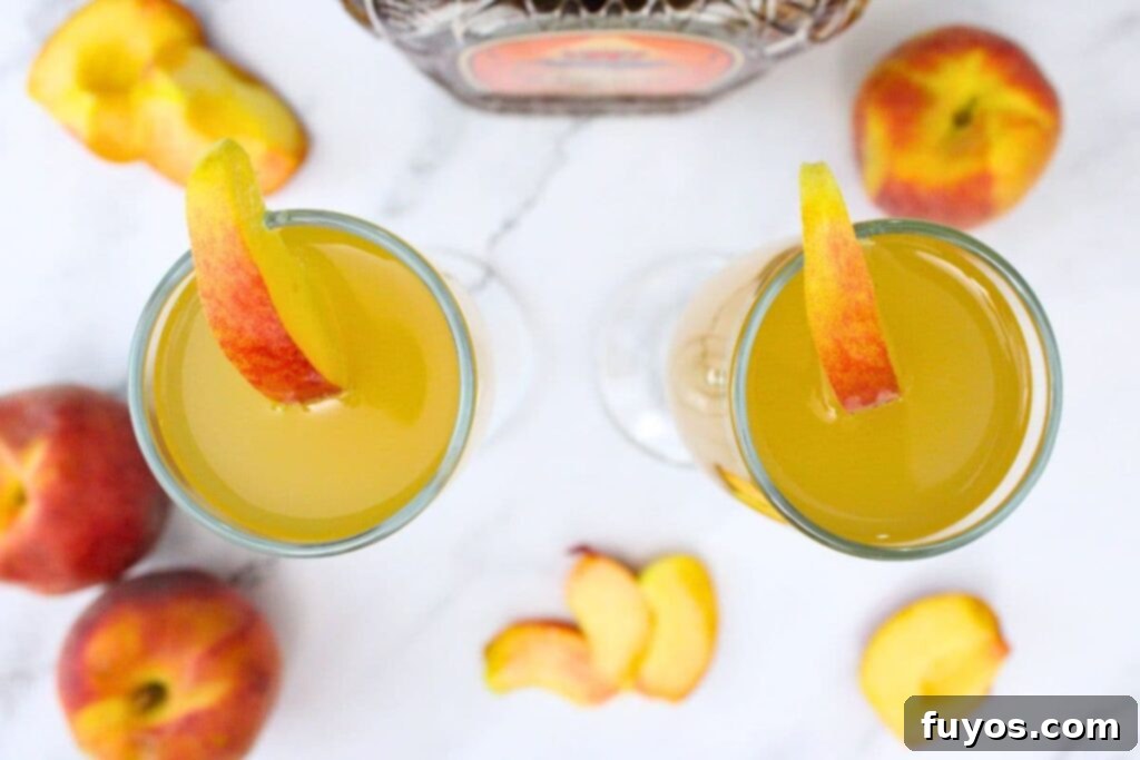 overhead view of two crown royal peach mimosa drinks with a fresh peach wedge