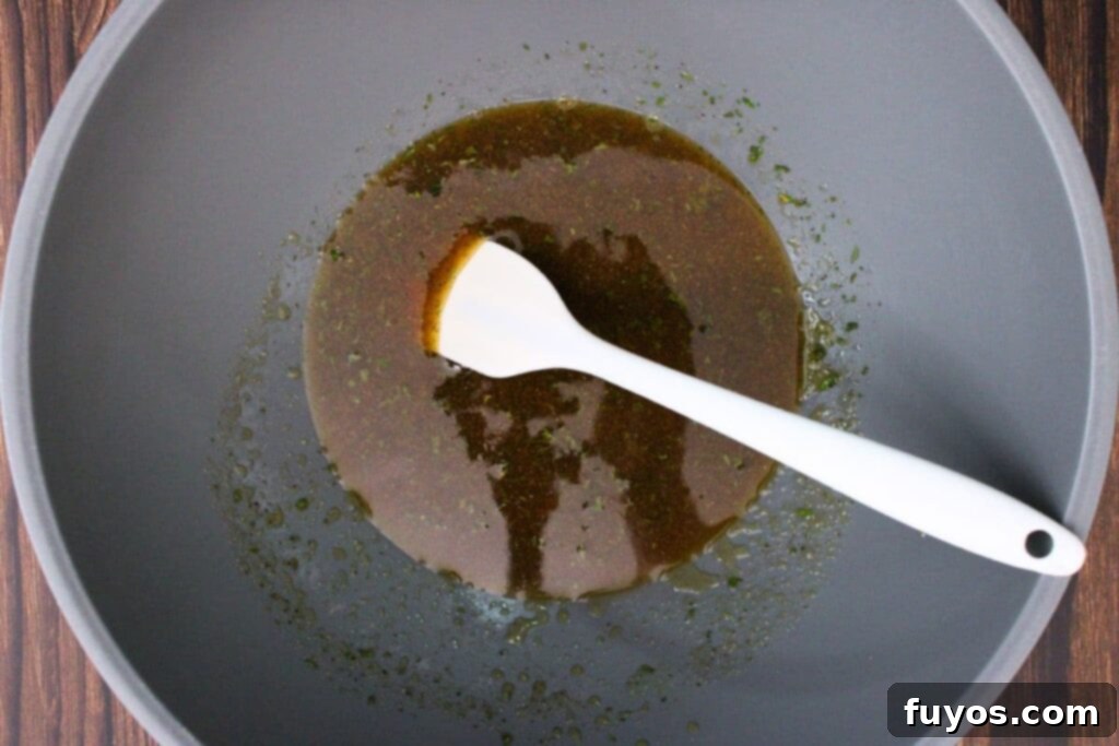 Close-up of a small bowl containing all the combined ingredients for the Crown Royal peach glaze, being whisked for blending