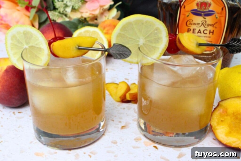 two peach whiskey sour cocktails sitting in front of a crown royal bottle