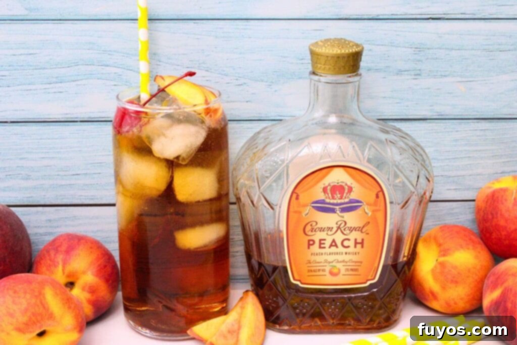 crown peach and cream soda cocktail next to crown royal peach whisky bottle in front of light wood background