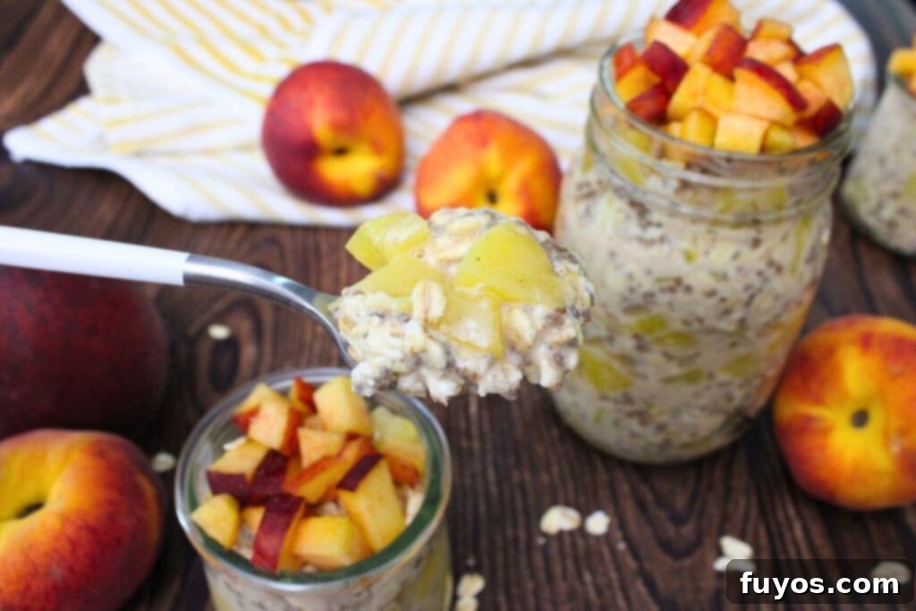 A hand holding up a spoon filled with creamy canned peach overnight oats, showcasing the tender peach chunks mixed within the oats.
