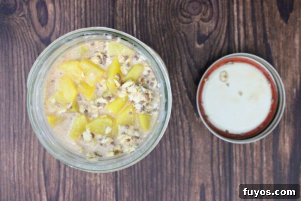 A mason jar filled with peach overnight oats, covered and sitting in the refrigerator, ready to soak overnight.