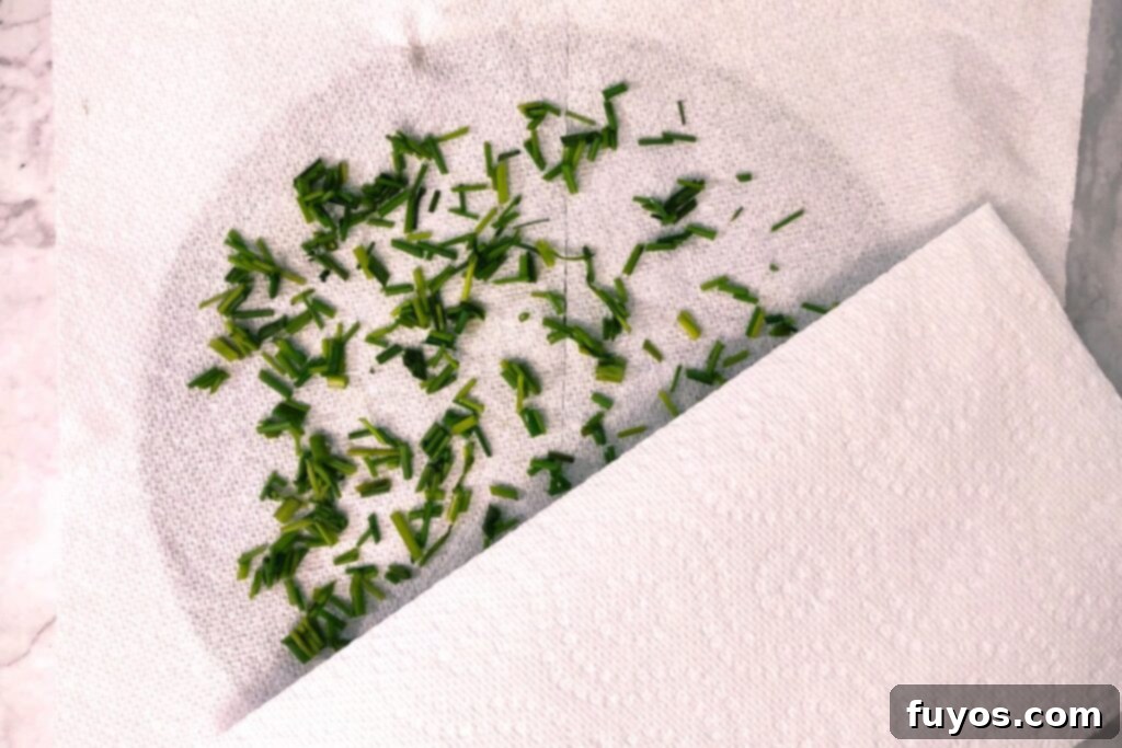 Two paper towels with chopped chives sandwiched in between, ready for microwave drying.