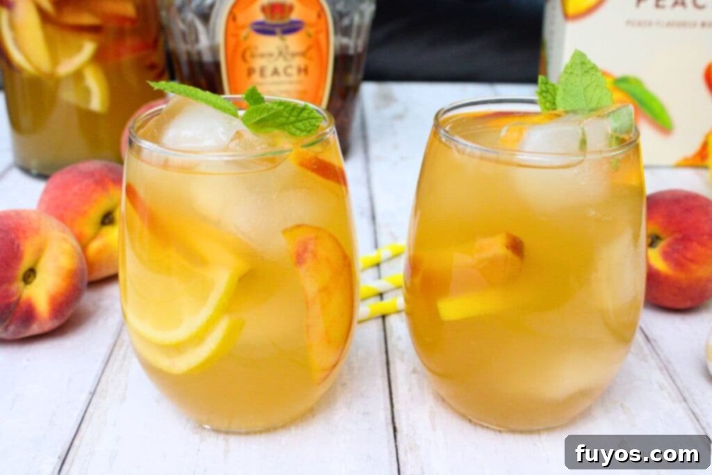two glasses filled with crown royal peach sangria on a white wooden table