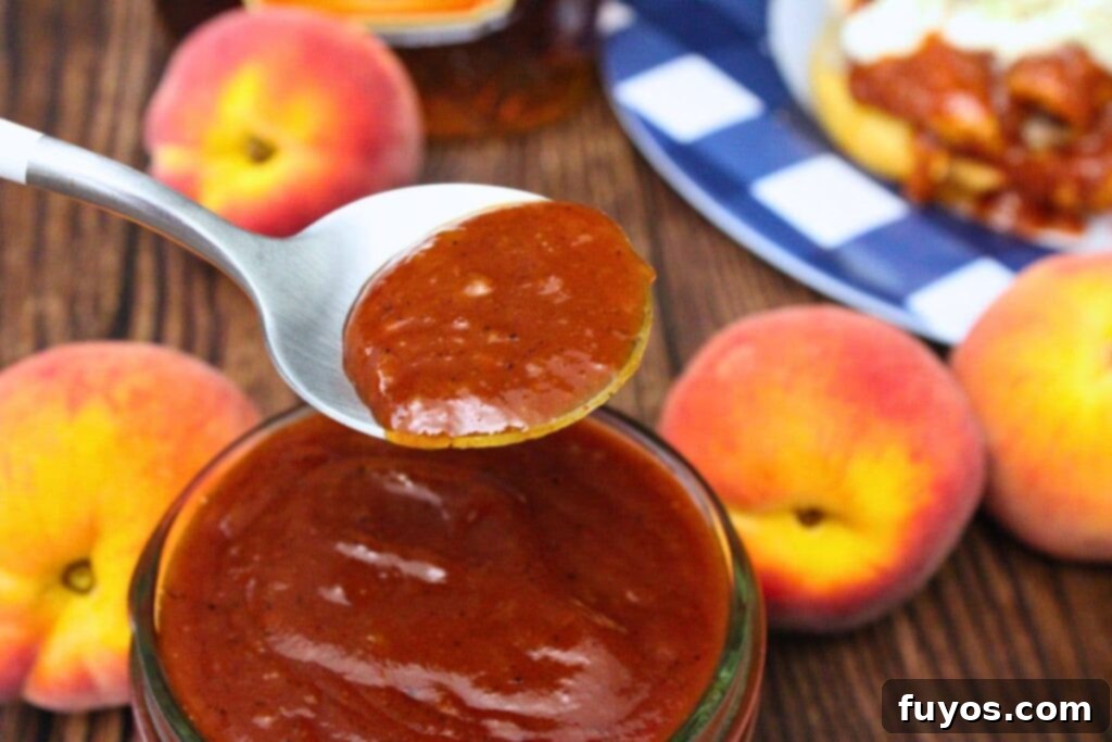 Whiskey Peach BBQ Sauce Homemade Microwave Ready 3 holding up a spoon of whiskey peach bbq sauce coming out of the jar